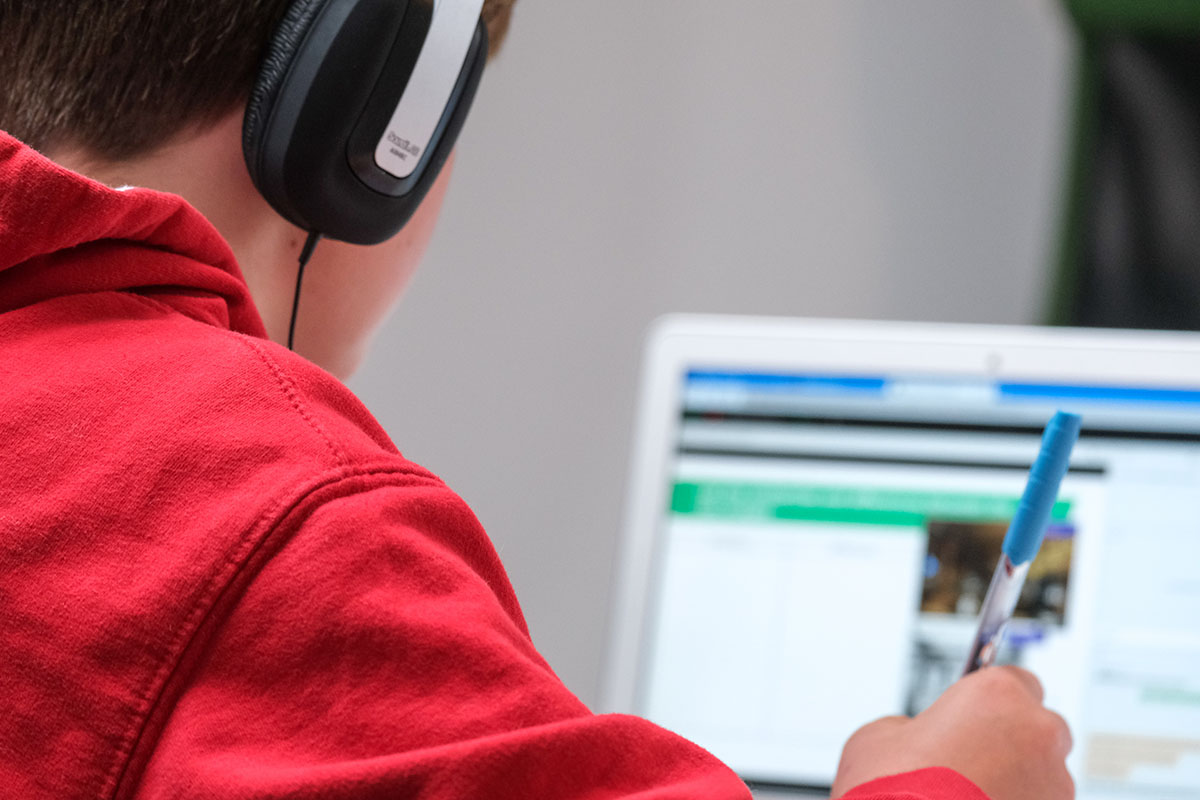 Ein Schüler nutzt digitale Angebote zum Lernen in der Schule. Lehrer:innen sollte mittels Fortbildungen die Einbindung digitaler Medien in den Unterricht vermittelt werden.